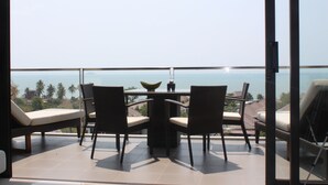 A balcony with a table and chairs, overlooking a scenic view of the ocean and palm trees. - Luxury apartment with beautiful sea view and large terrace (Klaeng District)
