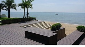 A wooden deck with steps leading to a sandy beach, palm trees, and a clear view of the sea. - Luxury apartment with beautiful sea view and large terrace (Klaeng District)