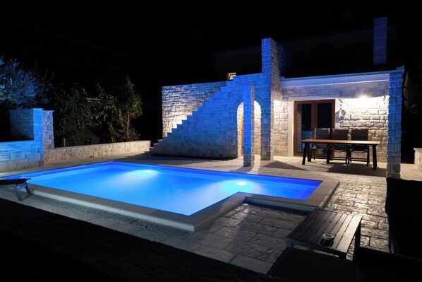 A swimming pool with a stone structure and a table with chairs.