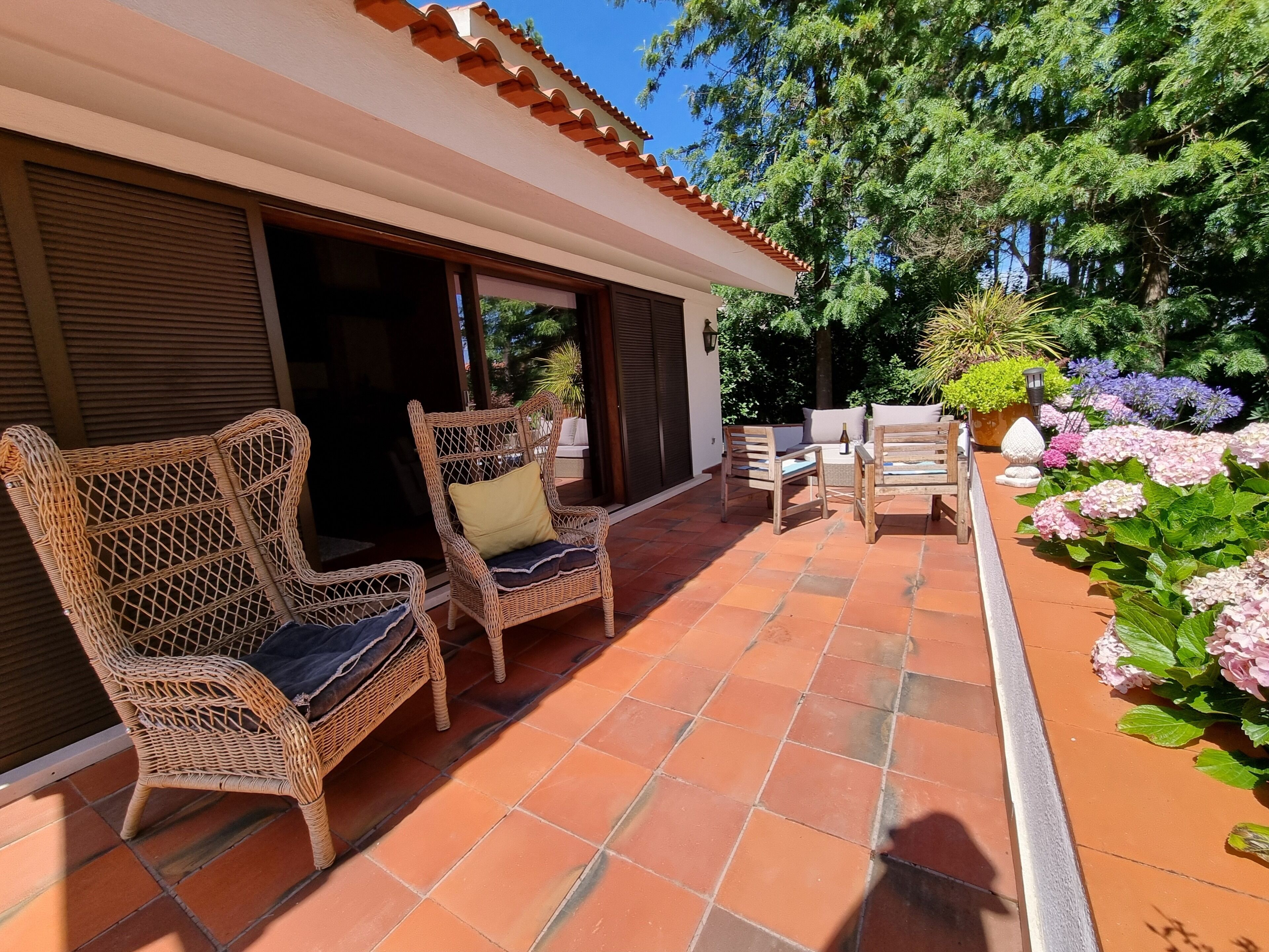 A covered outdoor seating area with wicker furniture and a tiled floor.