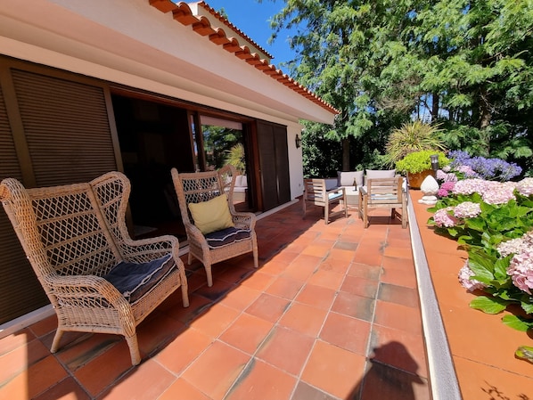 A covered outdoor seating area with wicker furniture and a tiled floor. - Architect Villa with private pool, 3 minutes to the beach and 20 min to Lisbon (Verdizela)