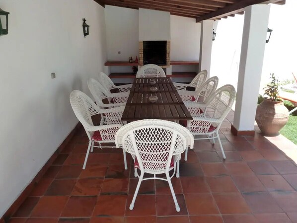 Une terrasse extérieure avec une table en bois et des chaises en osier blanc.