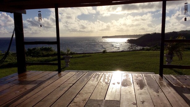 A wooden deck with a view of the ocean and grassy landscape. - Beautiful, spacious two bedroom apartment with lovely gardens and awesome views. (Saint John)