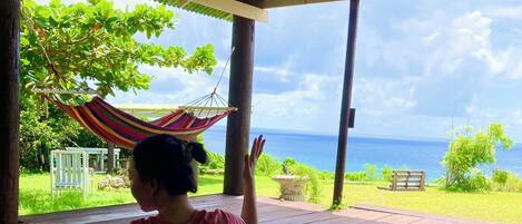 A person sitting on a yoga mat outdoors with a view of the ocean.