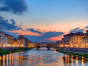 A river with buildings on either side, a bridge in the middle, and a sunset sky.