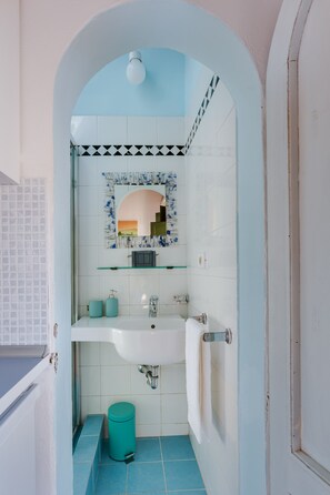 A bathroom with a white sink, a mirror, and a blue-tiled floor.