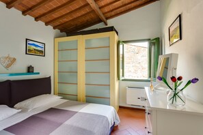 A bedroom with a bed, a wardrobe, a desk, and a window with a view of the outside.