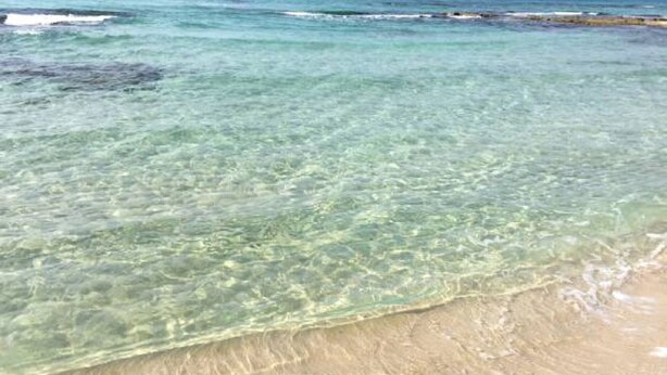 Een strand met helder ondiep water en een zandstrand.