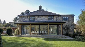 A stone house with a covered patio and a lawn.