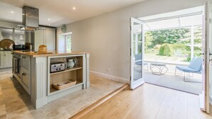 A modern kitchen with a central island, built-in oven, and a large sliding glass door leading to an outdoor patio.