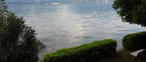 Un lac paisible avec un quai pour bateaux, entouré d’une végétation luxuriante et dominé par des montagnes en arrière-plan.