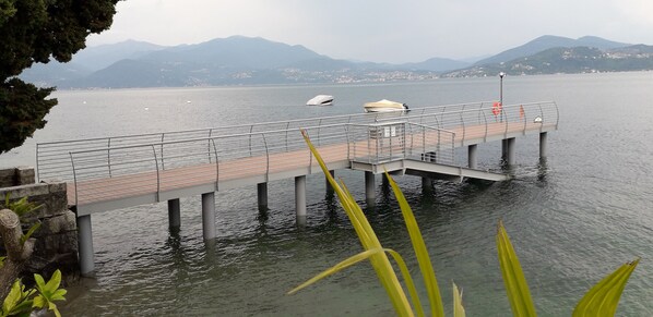 Un muelle se adentra en aguas tranquilas, con montañas al fondo.