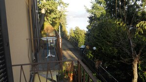 Un balcon avec une table et des chaises, donnant sur un lac et entouré d’arbres.