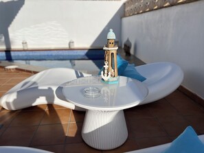 A small table with a decorative item on it, a pool in the background, and a white wall. - ABSOLUTE TRANQUILITY, COMFORTABLE AND CENTRAL LOCATION. (Tuineje)
