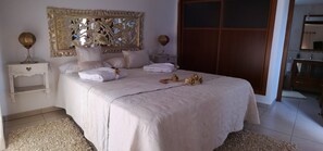 A neatly made bed with pillows and a blanket, a bedside table with a lamp, and a large mirror above the bed. - ABSOLUTE TRANQUILITY, COMFORTABLE AND CENTRAL LOCATION. (Tuineje)