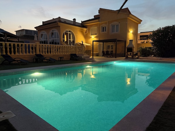 A swimming pool with a clear blue water surface, surrounded by a deck with lounge chairs and a covered seating area. - Beautiful villa, large heated pool, independent studio in ciudad quesada Wifi (Ciudad Quesada)