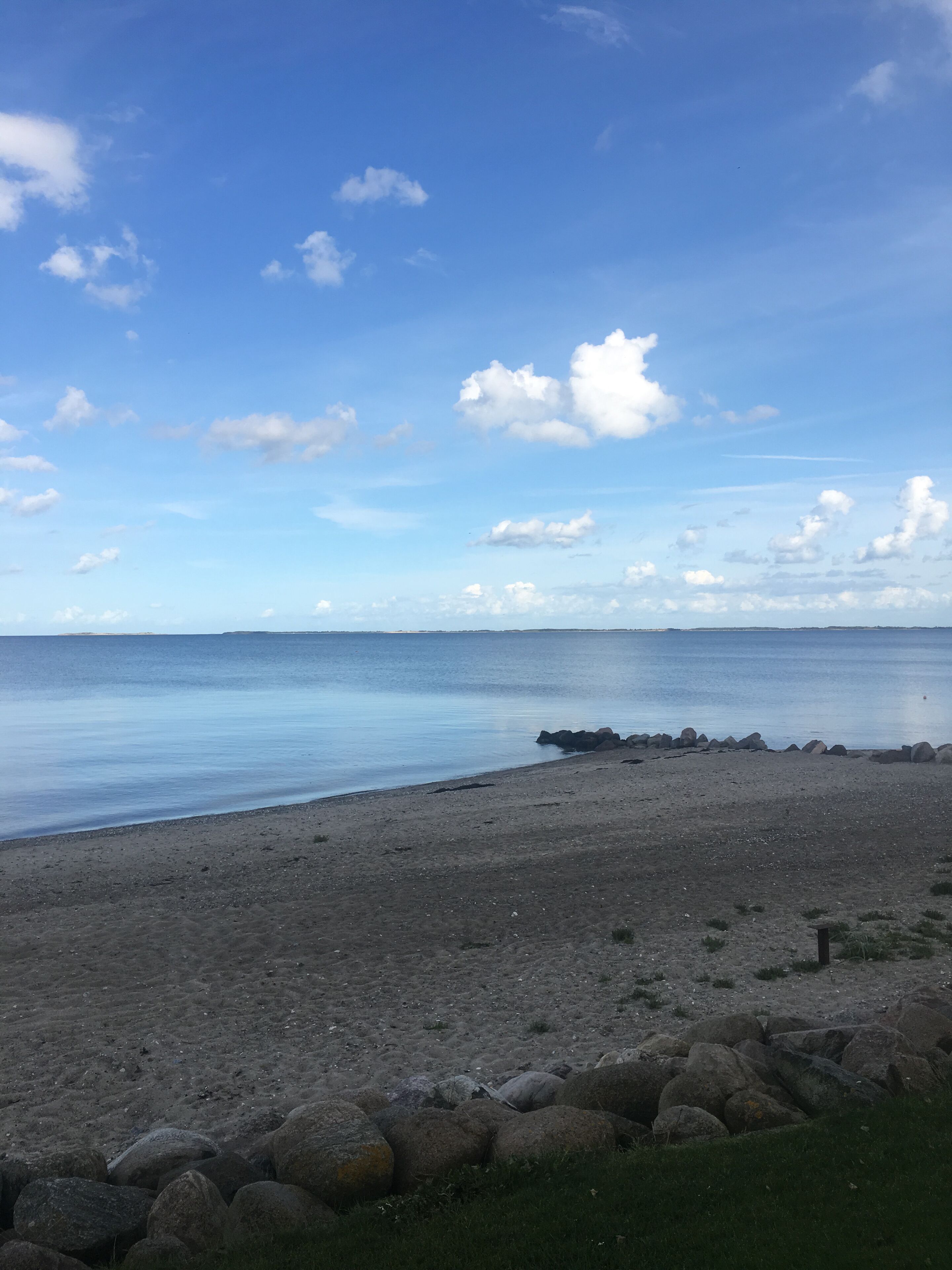 A beach with a rocky shoreline and calm water.