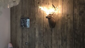 Une chambre avec un mur en bois, une tête de cerf accrochée au mur et une table de chevet avec une lampe.
