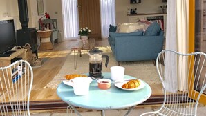 Un salon confortable avec un canapé, une table basse sur laquelle sont disposés des éléments pour le petit-déjeuner et un téléviseur.