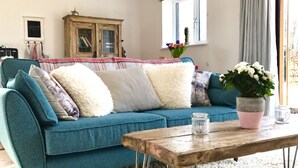 Un canapé de couleur turquoise agrémenté de plusieurs coussins, une table basse en bois et une plante en pot.