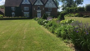 Une grande maison de style traditionnel, dotée d’une pelouse et d’un jardin bien entretenus.