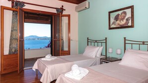 A hotel room with two beds, a view of the sea, and a painting on the wall. - Vill Pergola Elli, holiday apartment in Corfu, Greece with stunning sea view! (Corfu)