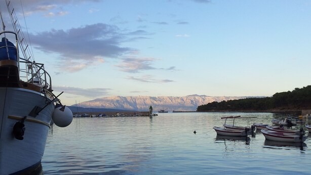 A calm lake with boats docked, a large ship on the left, and mountains in the background. - Apartment for 4 persons in Jelsa on the island Hvar (Jelsa)
