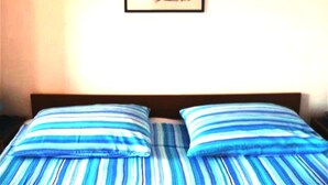 A bed with striped bedding and a framed picture on the wall. - Apartment for 4 persons in Jelsa on the island Hvar (Jelsa)