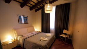 Una camera da letto con un letto, lampade sui comodini, una sedia, un lampadario e un quadro appeso al muro.