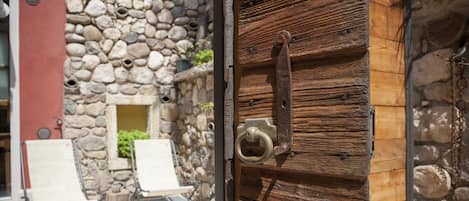 Step into a charming outdoor space with a rustic door, potted plant, and comfortable lounge chairs.