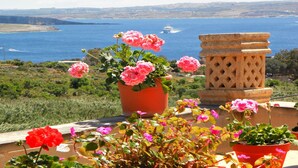 A terrace with potted flowers and a view of the sea. - Great Location: FREE Gozo transfers, WIFI, Bicycles & BBQ  – NO Car required! (Ghajnsielem)