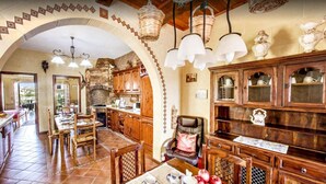 A rustic kitchen with wooden cabinets, a stone fireplace, and hanging light fixtures. - Great Location: FREE Gozo transfers, WIFI, Bicycles & BBQ  – NO Car required! (Ghajnsielem)