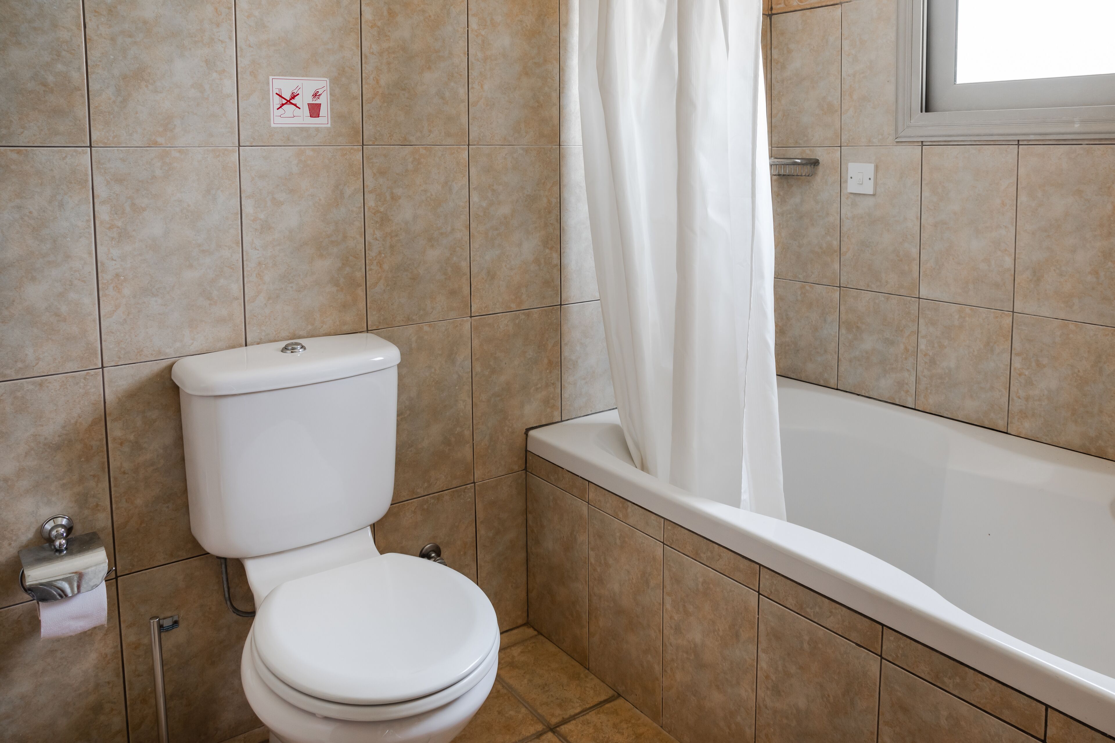 Een badkamer met toilet, bad en douchegordijn.
