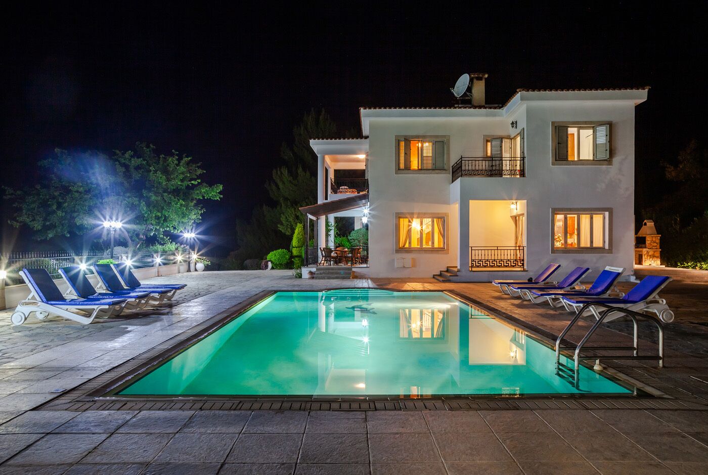 Ein zweigeschossiges Haus mit Schwimmbad, Sitzgelegenheit im Freien und einer Satellitenschüssel.