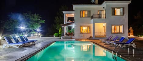 A two-story house with a swimming pool, outdoor seating, and a satellite dish.