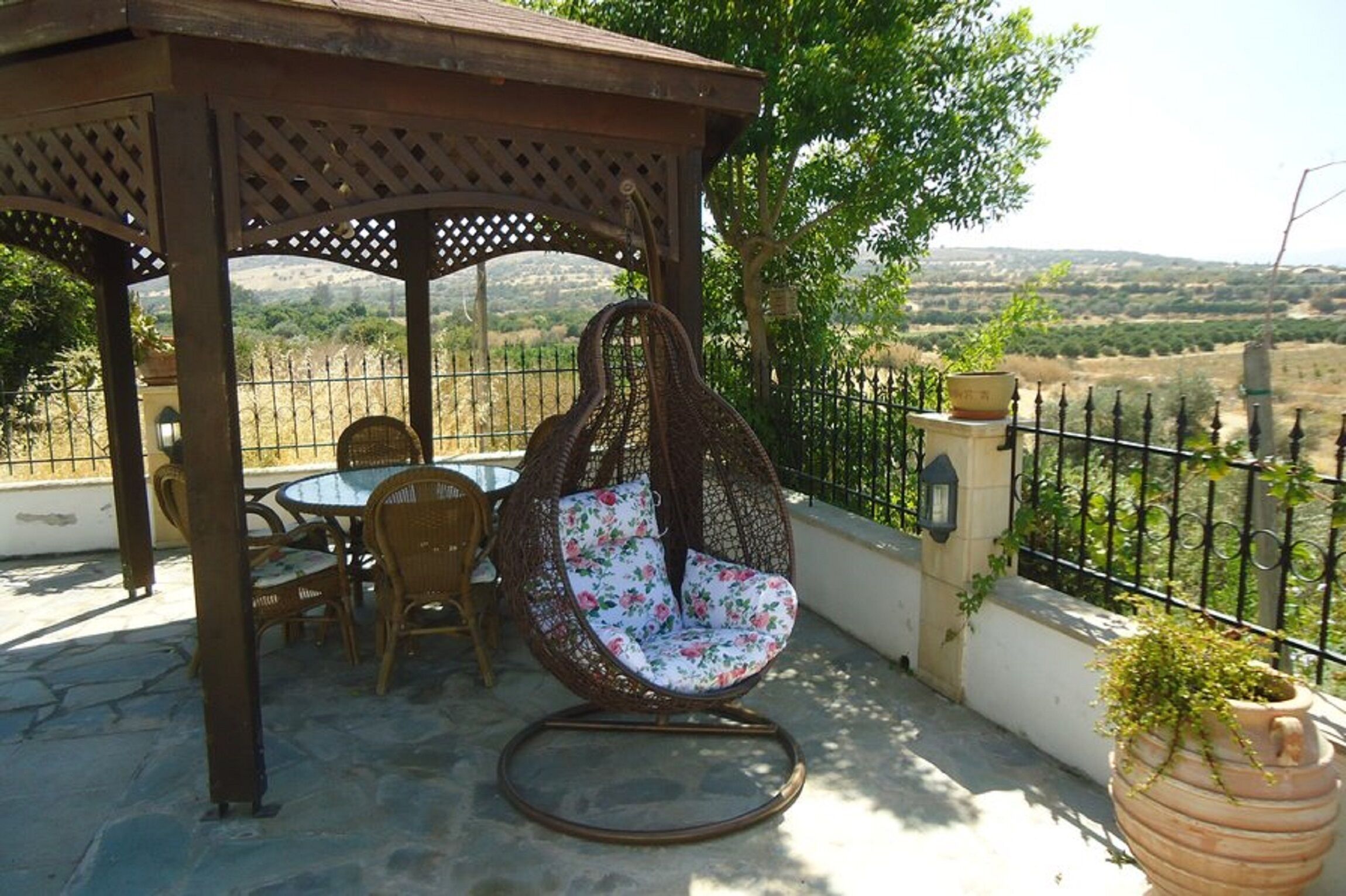 A patio with a wicker chair, a table, and chairs.