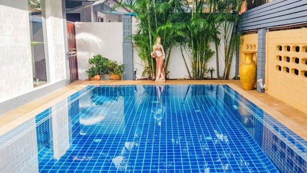 A swimming pool with blue tiles, surrounded by potted plants and a decorative wall. -  ⭐⭐⭐⭐⭐Villa 4 bedrooms with private pool 5 minutes beaches and Walking Street. (pattaya)