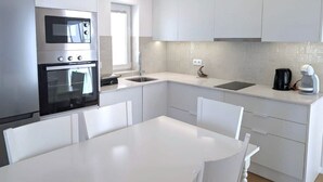 A modern kitchen with white cabinetry, a built-in oven, a sink, and a coffee maker.