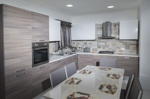 Enjoy cooking in this well-equipped kitchen with an oven, stainless steel range hood, and sleek cabinetry.