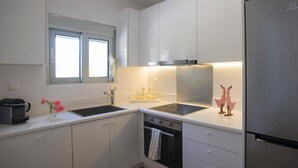 Eine moderne Küche mit weißen Schränken, einem Edelstahlkühlschrank, einer doppelten Spüle und einem Fenster über der Spüle.