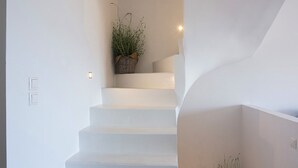 Eine moderne Treppe mit weißen Stufen, Holzgeländern und Blumentöpfen oben und unten.