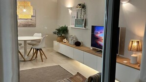 A modern living room with a dining area, a TV, and a kitchen. - Saltwater Apartment - Sea View (Portimão)