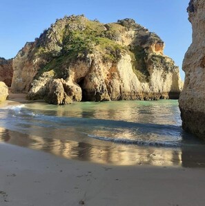 Ein Strand mit klarem Wasser und felsigen Klippen.