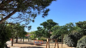 Un parc amb una àrea de jocs, seients i arbres.