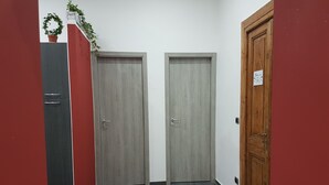 A hallway with two closed doors, a red cabinet, and a wooden door with a sign. - HOLIDAY HOME Central Station, Business Center, Naples city center, Mary's Room (Napoli)