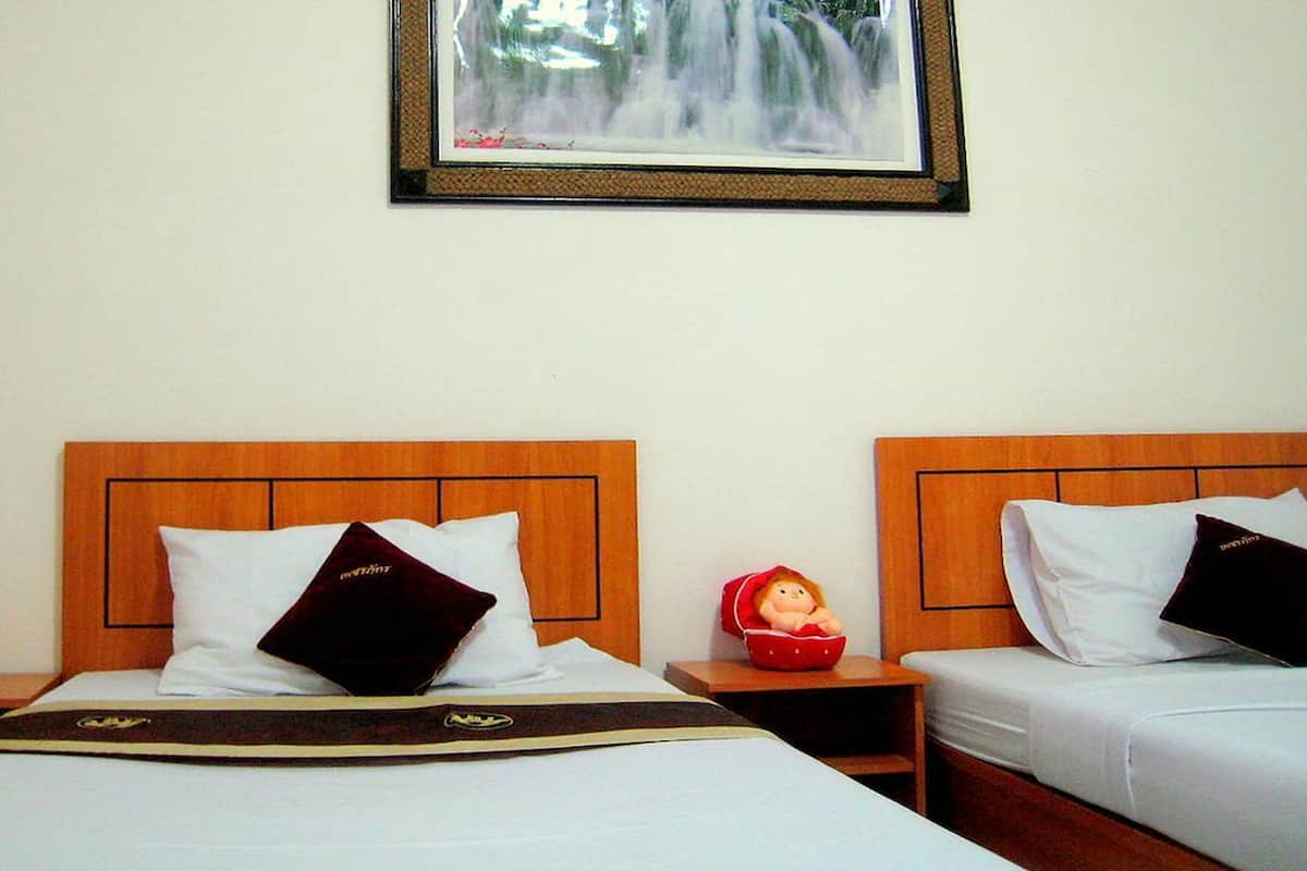 A hotel room with two beds, each with a wooden headboard, white bedding, and a framed picture above the beds.