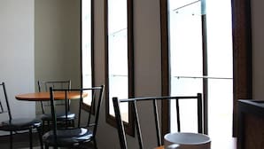 Un espace repas comprenant une table et des chaises, de grandes fenêtres et une vue sur l’extérieur.