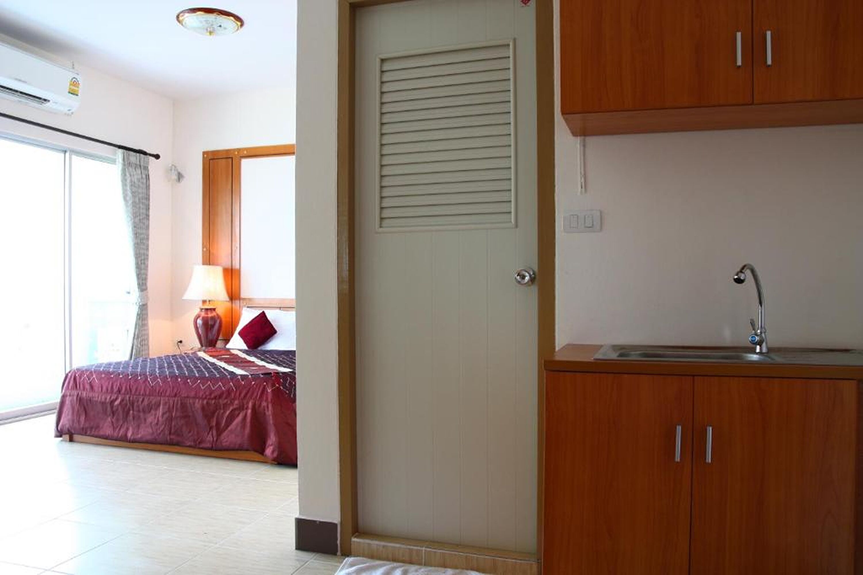 A bedroom with a bed, a bedside table with a lamp, and a window with curtains.