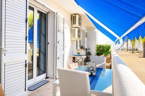 Un patio con tavolo e sedie, un condizionatore d'aria e un tendaggio blu.