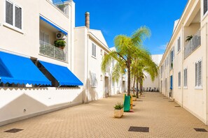 Un stretto vicolo lastricato con edifici bianchi, tende blu e una palma.